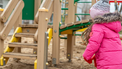 Little girl having fun on playground. Happy healthy little child climbing, swinging and sliding on...
