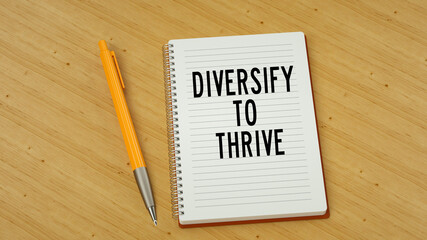Diversify to thrive text message on note pad. Wooden background and pen 3d render.
