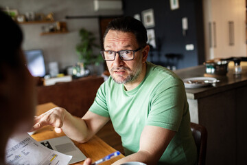 Stressed man managing finances and bills at home on laptop