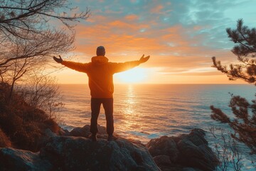 Fototapeta premium Hiker celebrating sunrise over the ocean with open arms