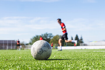 Soccer Ball On Lush Green Field With Player Running In The Background