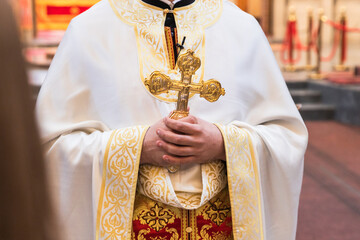 Priest in Ornate Vestments Holding a Golden Cross During an Orthodox Religious Ceremony