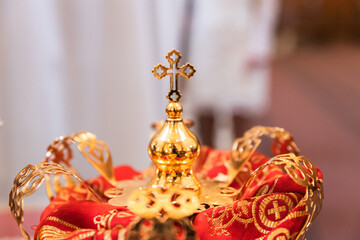 Ornate Golden Crown with Cross Resting on Embroidered Red Fabric in a Sacred Setting.