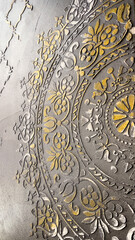 Golden and silver embossed floral mandala pattern on black wall, elegant and ornate detail, interior design, concept of luxury décor, modern art, textured surface, cultural influence, fine detail