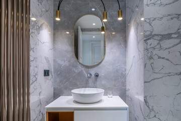 Modern bathroom design with an elegant sink, marble walls and stylish fixtures.