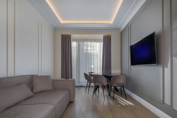 Fototapeta premium A cozy room with a modern interior in the sunlight. There is a seating area with a sofa and a TV.
