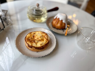 Pastry tart and glazed cake served with herbal tea on a cafe table. Cozy break and slow lifestyle with light sweet food