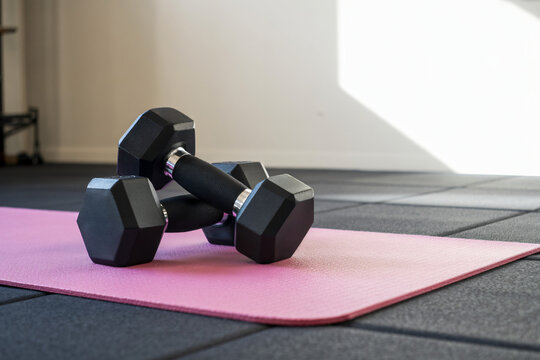 adjustable neoprene dumbbells placed on high-performance yoga mat