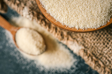 Close-up of semolina in a wooden spoon with a bowl in the background. Soft natural lighting...