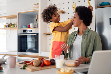 Playful African Mother and Daughter Cooking Together in a Bright Modern Kitchen