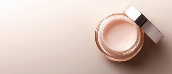 Jar of cream or lotion on a beige background. the jar is round and has a silver lid with a black stripe on the top. the cream itself is a light pink color and appears to be smooth and creamy.