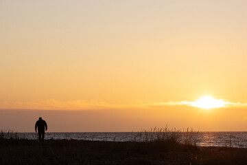 Mann spaziert an der Ostsee bei Sonnenuntergang.