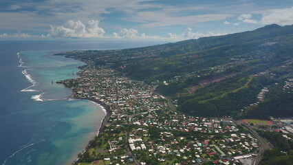Breathtaking aerial view showcasing the stunning coastline of Tahiti, with colorful houses nestled...