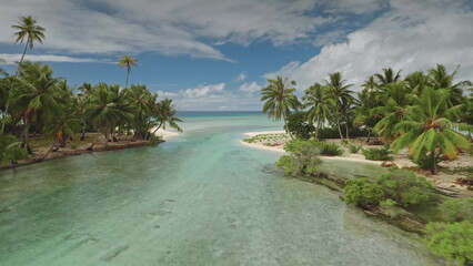 Shallow river channel flowing into turquoise water of blue ocean in Fakarava, UNESCO biosphere reserve, Tuamotu archipelago, French Polynesia. Palm trees and sand beach tropical islands. Drone flight