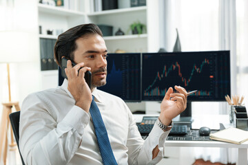 Trader businessman calling to consultant or partner with two stock exchange investment, compare...
