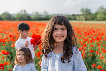 three children standing in the big field of poppies