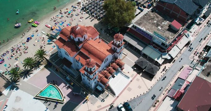 Stunning aerial perspective depicting a church located near a lively coastal beach in Paralia, Greece
