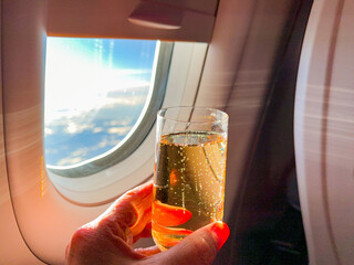 Person holding a glass of champagne in the business class cabin of a passenger jet