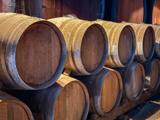 Large oak barrels in the cellar of a vineyward being used to age wines. No people.