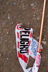 Scattered red-white caution tape fragments and copper pipe resting on gravel, suggesting recent...