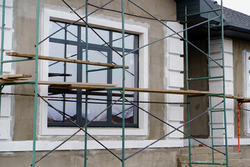 Private cottage house building under construction with plastered walls, architectural elements and...