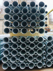 A stack of new tall conical metal lamp posts on wooden pallets at a infrastructure construction site