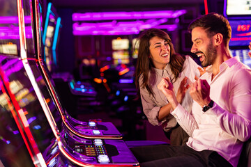 Happy Couple Celebrating a Win at a Vibrant Casino Slot Machine