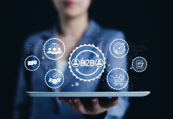 B2B Marketing and Business Collaboration Strategy Concept. Businesswoman hold tablet displaying B2B marketing icons, symbolizing business-to-business communication, collaboration, trade, and strategy.