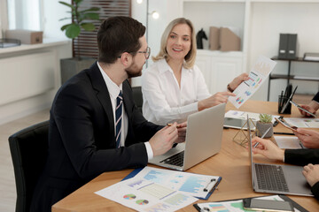 Coworkers working together at wooden table in office