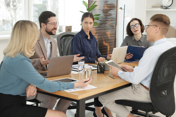 Coworkers working together at wooden table in office