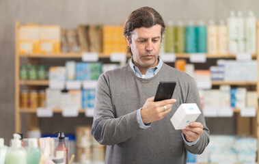 Adult man buyer scanning qr code for box of ointment in pharmacy