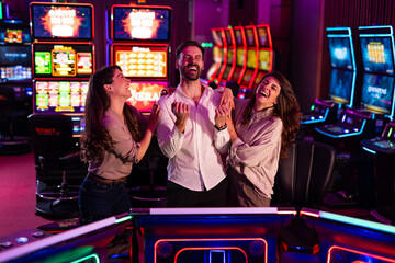 Friends Laughing Together While Enjoying Slot Machines at a Casino