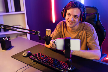 Enjoy smart gaming streamer with control joystick, playing game online of live streaming by smartphone rec with team skilled players on computer at modern technology cyber neon light room. Pecuniary.