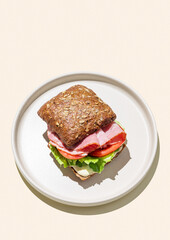 Toast sandwich made of grain bread with prosciutto, cheese, tomatoes, lettuce and sauce on yellow background
