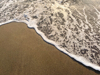 Black Sea waves and sandy beach with water during sunset or sunrise.