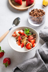 Natural Greek yogurt with homemade chocolate granola, strawberries and banana in a bowl
