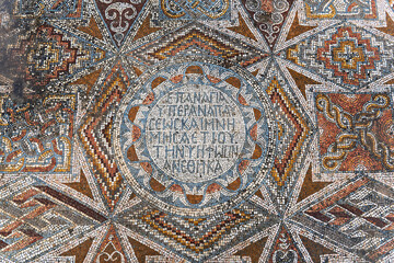 Intricate Byzantine mosaic featuring geometric patterns and a central Greek inscription on a floor of ruined ancient church in Hurvat Beit Loya, Israel