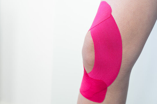 A close-up of an athlete’s injured knee with kinesiology tape applied. For content focused on injury treatment, recovery, and sports therapy.