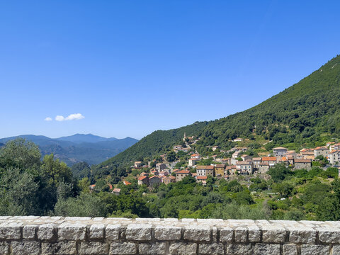 Ocana, Corsica, France - July 8, 2024: Green mountain landscape. Over a steep canyon, look from one side of the village to the other side. Residential buildings with red roofs