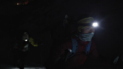 A close-up shot of a group of hikers trekking through the dark, their headlamps illuminating their determined faces, emphasizing the bond and resilience of the team. © wkproduction