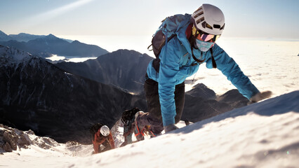 A dynamic wide-angle shot captures a group of climbers ascending a snowy mountain, showcasing their teamwork and determination. © wkproduction