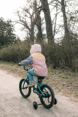 Little girl cycling on path in spring park