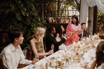 A Black groom and bride with a multinational group of guests at their wedding celebration, sharing...
