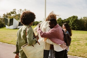 A multinational group of young people, a Black young man, a White young man, and a Black young...