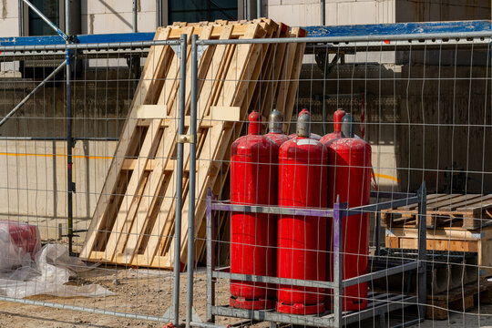 Red gas cylinders and wooden pallets at a construction site