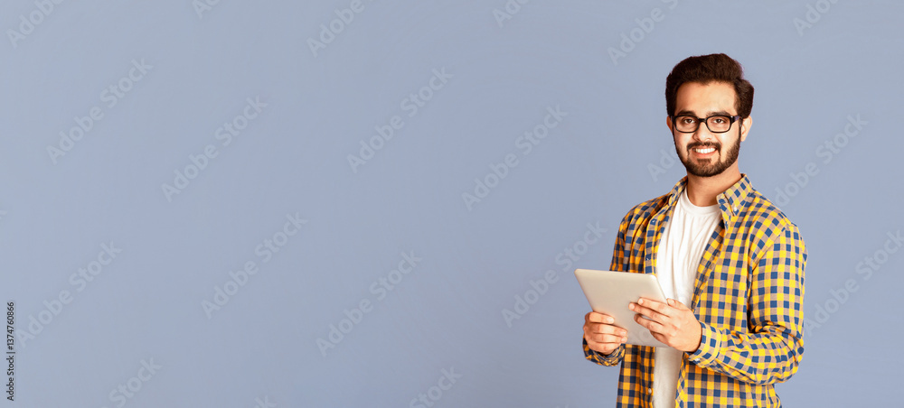 Poster online work, education or communication. funky indian man using tablet computer on violet studio bac
