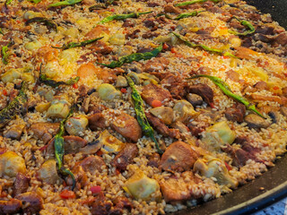 Rustic meat paella with rice, green peppers, artichokes, and mushrooms freshly cooked