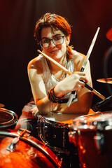 Drummer holding drumsticks posing at concert with stage lights