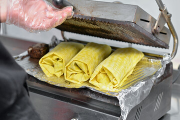 Freshly grilled shawarma wraps on a hot press in a street food kitchen