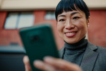 Smiling businesswoman using smartphone in urban setting